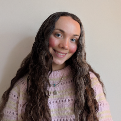 Rosanna Clarke smiling in a soft pink knit jumper